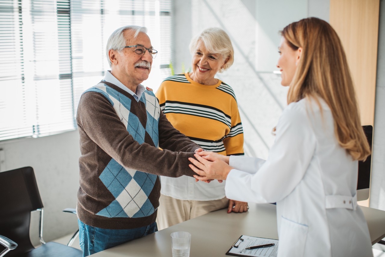 Senior couple at doctor's office. Female doctor talking to them with smile.